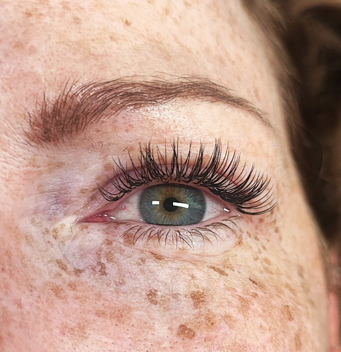 Natürliche Wimpernverlängerung in 1:1-Technik an einem grünen Auge