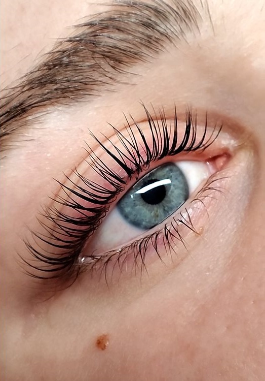 Kräftig geschwungene Wimpern nach einem Korean Lashlift an einem blauen Auge